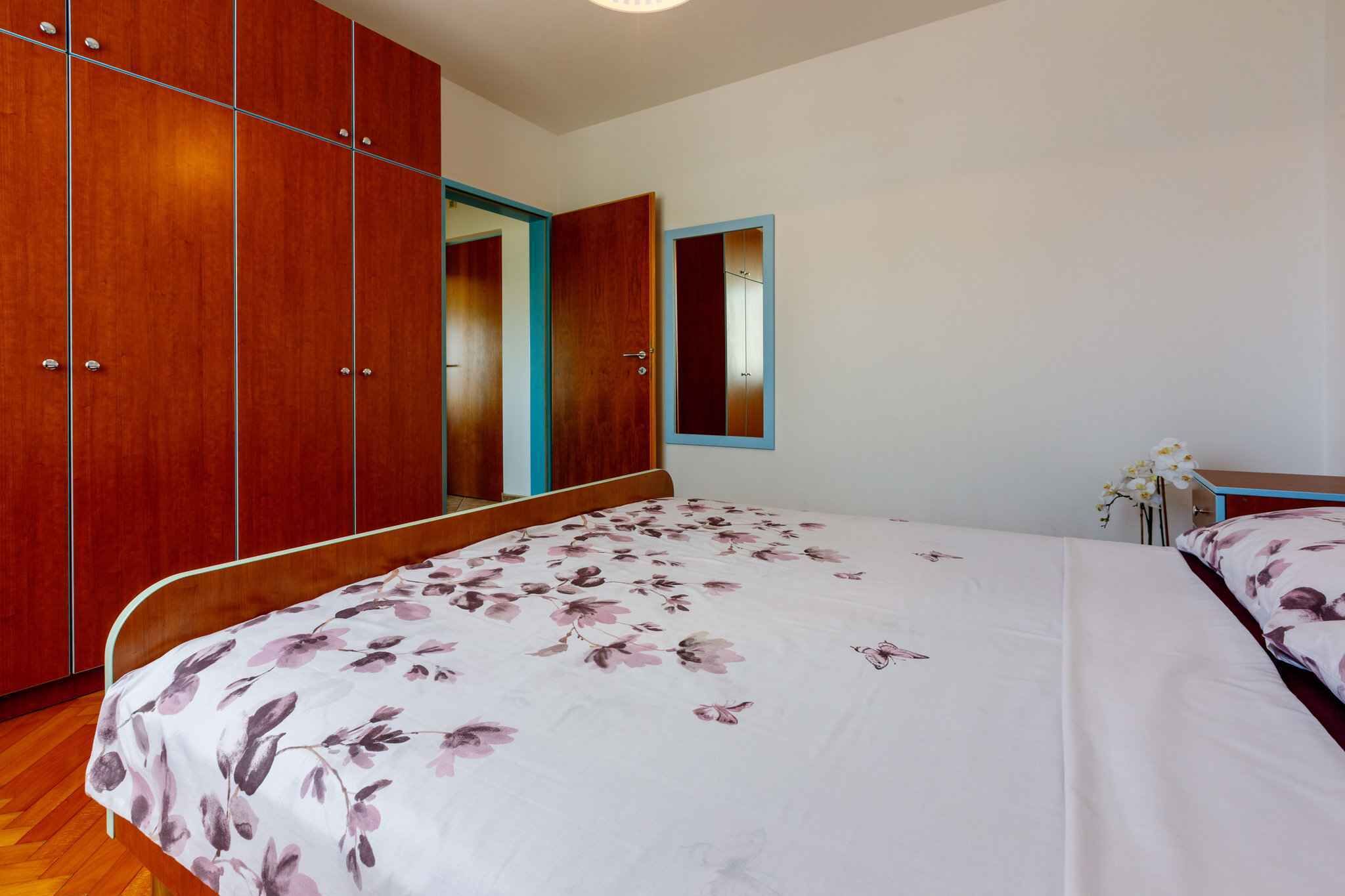 Een slaapkamer met een bed, een houten garderobe en een spiegel.