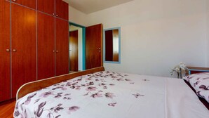 A bedroom with a bed, wooden wardrobe, and a mirror. - Holiday apartment with balcony and air conditioning (Crikvenica)