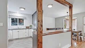 Een moderne keuken met witte kasten, een houten eiland en een eethoek met een tafel en stoelen.