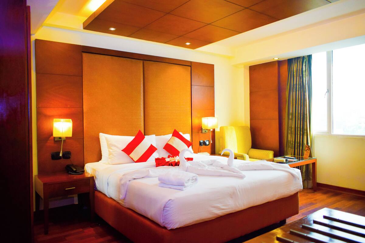 A hotel room with a large bed, a nightstand with a phone, a desk, and a chair.
