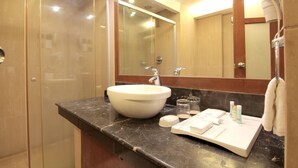 A bathroom with a large white sink, a glass shower enclosure, and a mirror above the sink. - Fortel (Chennai)