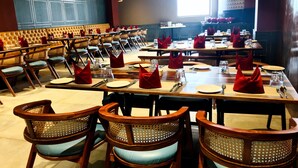 A restaurant with multiple tables set for dining, featuring wooden chairs and red napkins. - Fortel (Chennai)