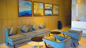 A modern lobby with a sofa, armchairs, and a coffee table. There are four framed paintings on the wall. - Fortel (Chennai)