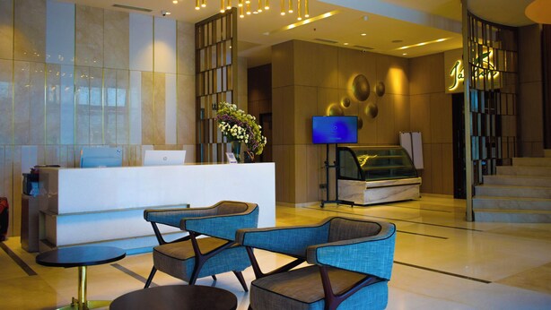 A modern hotel lobby with a reception desk, seating area, and a staircase. - Fortel (Chennai)