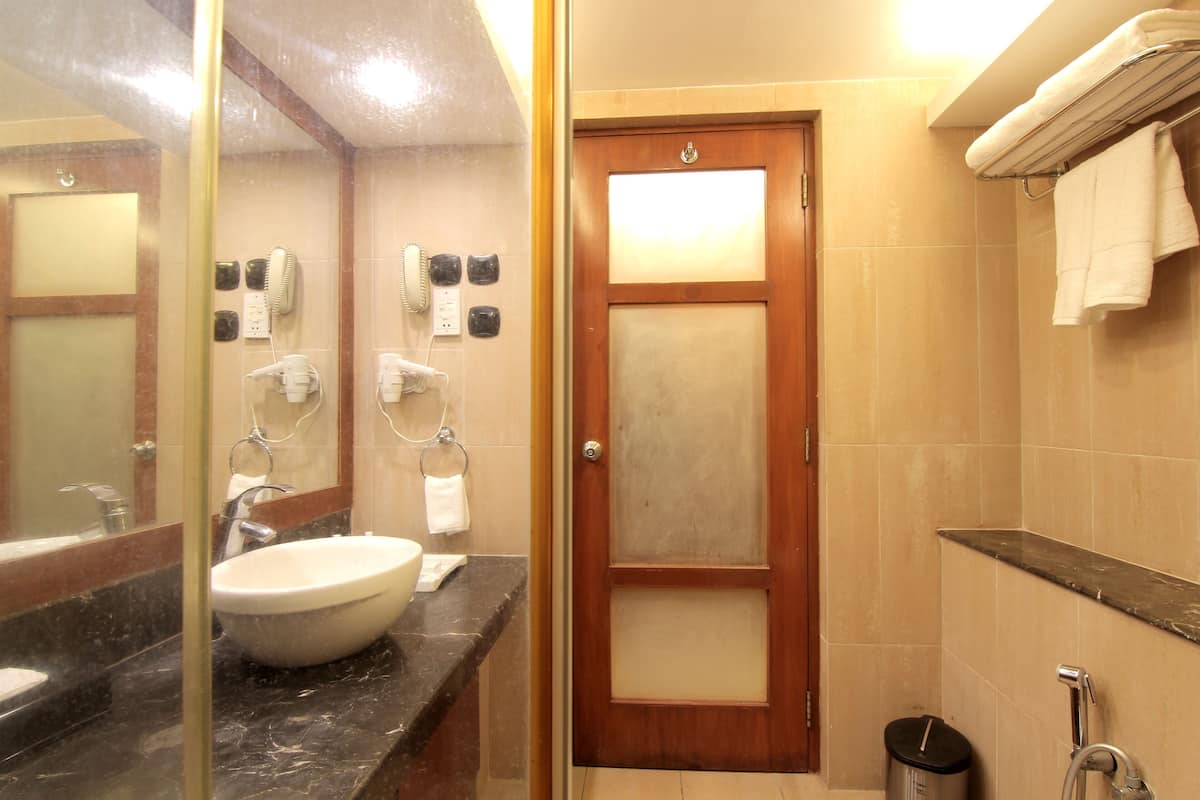 A bathroom with a sink, mirror, towel rack, and a door.