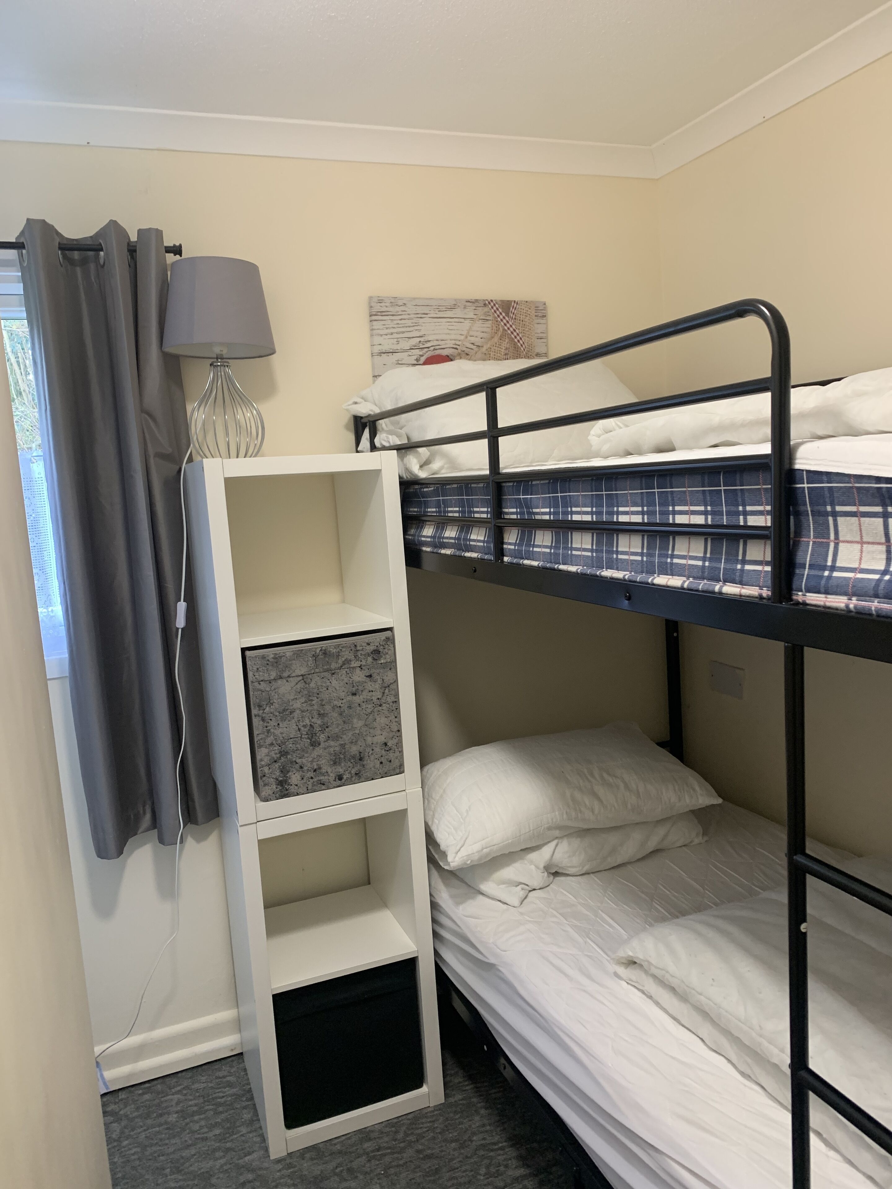 A bunk bed room with a desk and a lamp.