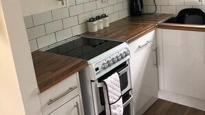 Eine moderne Küche mit weißen Schränken, einem Gasherd, einem Backofen und einer Kaffeemaschine.