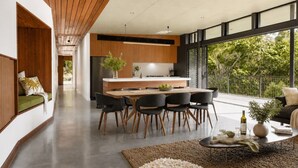 Une cuisine moderne dotée d’un îlot central, d’un coin repas avec des chaises et d’une vue sur la verdure environnante.
