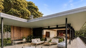 Un espace piscine extérieur moderne, doté de sièges et d’un patio couvert.
