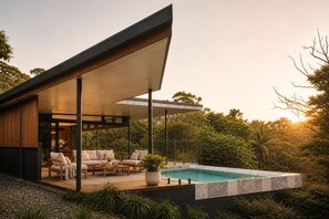 Een modern huis met een zwembad, buitenmeubels en weelderige begroeiing.