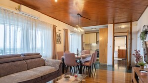Una sala de estar moderna con techo de madera, un sofá, una mesa de centro de vidrio y un comedor con sillas y una mesa.