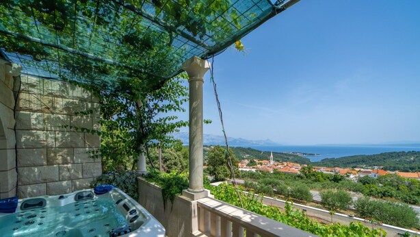 Un jacuzzi en un balcón con vistas a un pueblo costero y montañas.