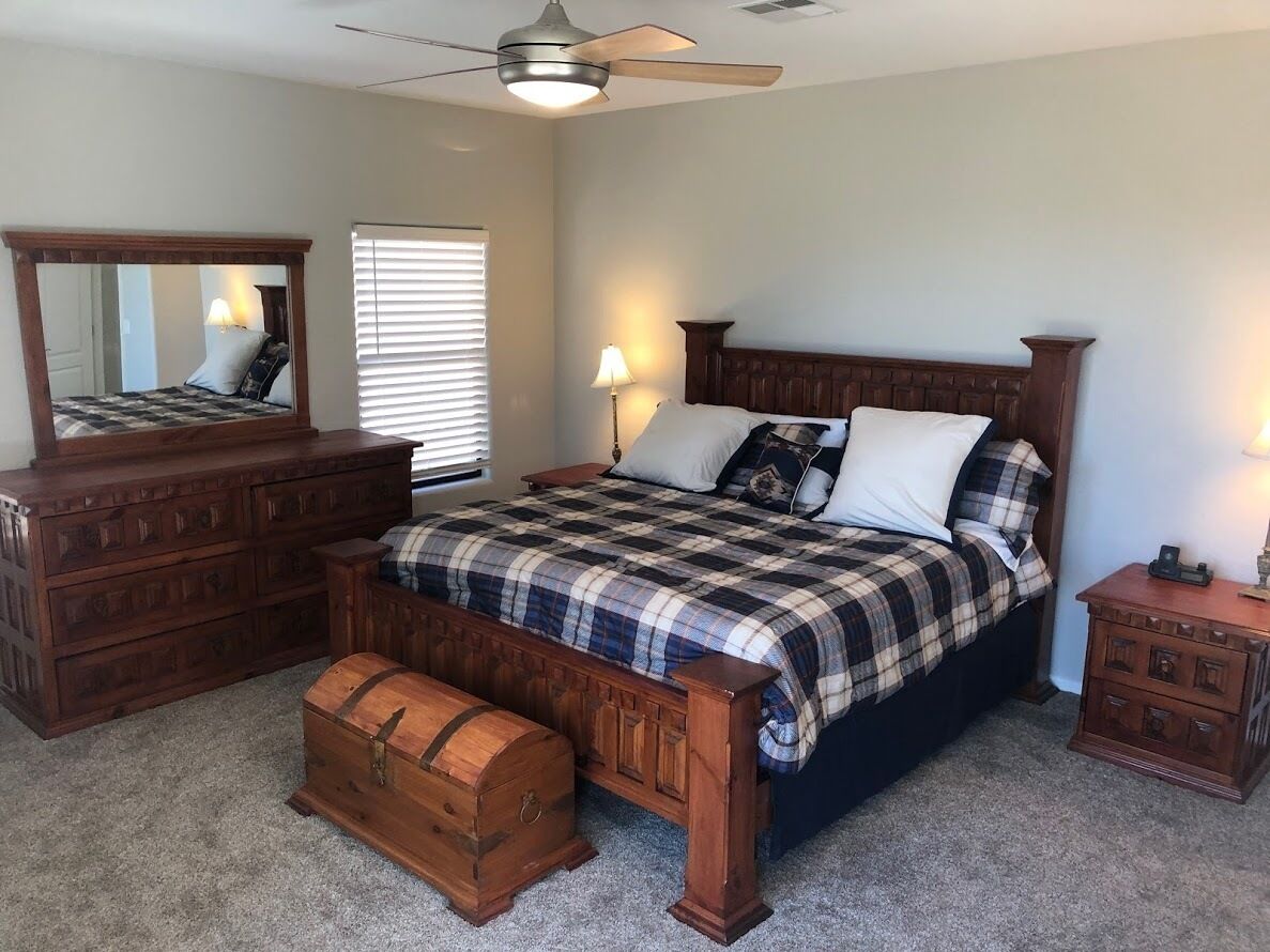 A bedroom with a bed, dresser, nightstand, and a trunk.