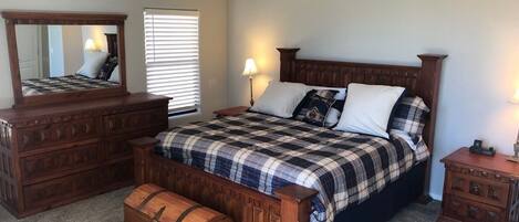 A bedroom with a bed, dresser, nightstand, and a trunk.