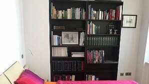 Ein Schlafzimmer mit einem Bett, Kissen und einem Bücherregal an der Wand.