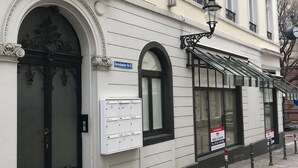 Ein Gebäude mit einem großen Bogenportal, einem Schild mit der Aufschrift 'Gemsbacher St 32' und einem Fenster mit dem Hinweis 'To Remain'.