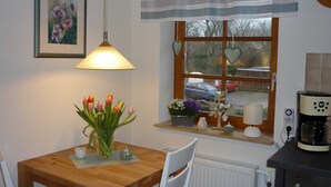 Un coin repas chaleureux avec une table en bois, un vase de tulipes et une fenêtre donnant sur les voitures garées.