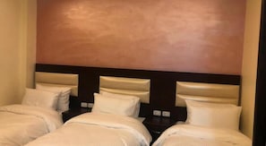 Quarto de hotel com duas camas, cada uma com roupa de cama branca e cabeceiras.