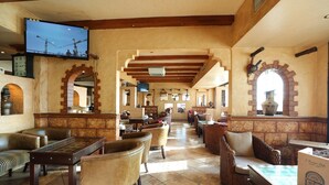 A spacious lobby with high ceilings, wooden beams, and a television mounted on the wall. There are multiple seating areas with wicker furniture and a tiled floor. - OYO 112 Semiramis Hotel (Manama)