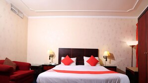A hotel room with a large bed, two bedside tables, a red armchair, and a wardrobe. - OYO 112 Semiramis Hotel (Manama)