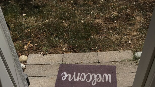 A welcome mat and a doormat at a building entrance.