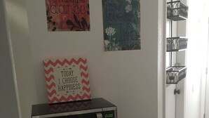 A kitchen area with a microwave, a refrigerator, and a trash bin. There are motivational posters on the wall.