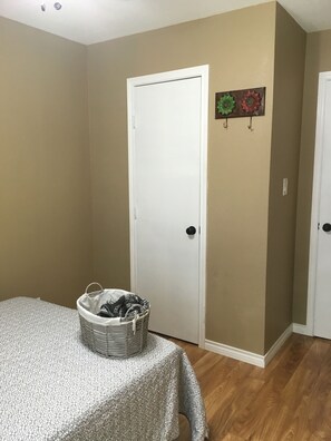 Un dormitorio con cama, una puerta, decoración en la pared y una cesta en el suelo.