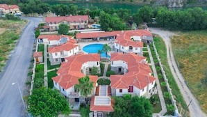 Een resort met meerdere villa’s, een centraal gelegen zwembad en een meer op de achtergrond.