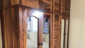 A wooden wardrobe with mirrored doors and a handle.