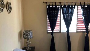 A bedroom with a bed, a lamp, and a window with curtains.