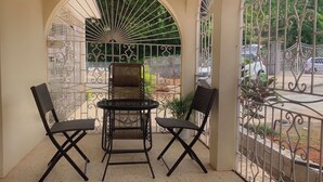 A balcony with a table and two chairs, surrounded by decorative metal railings.