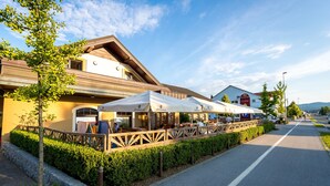 A restaurant with outdoor seating along a street, a clear sky, and a pedestrian path.