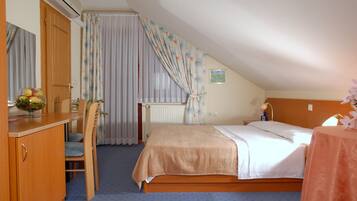 A bedroom with a bed, a desk, a chair, and a radiator.