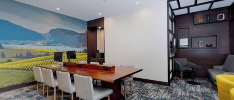 Une salle de conférence moderne, dotée d’une grande table, de chaises blanches et d’une fresque représentant un paysage.