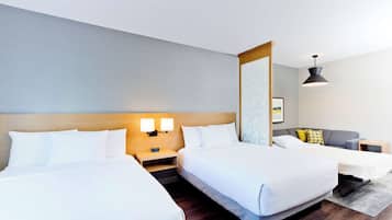 A hotel room with two beds, a sofa, a desk, and a large mirror.