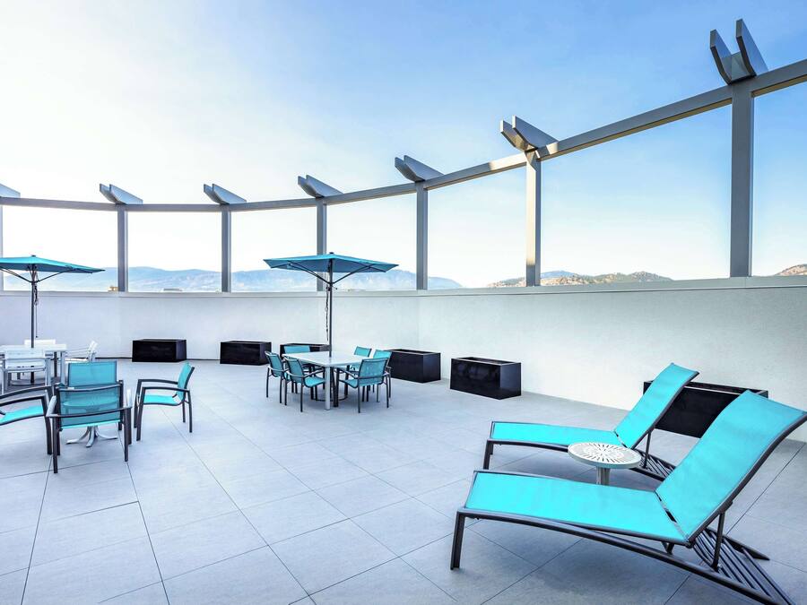 Eine Dachterrasse mit moderner Einrichtung, darunter Loungemöbel und ein Esstisch, unter einer Glaskuppel mit Solarzellen.