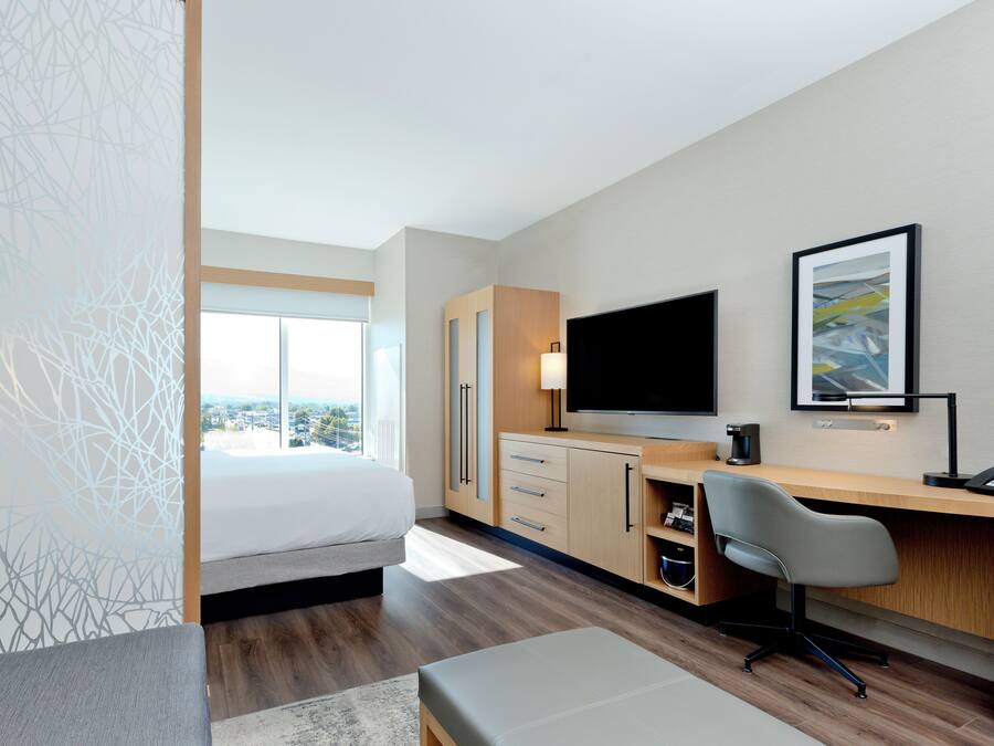 Une chambre d’hôtel moderne équipée d’un lit, d’un bureau, d’une chaise et d’un téléviseur.