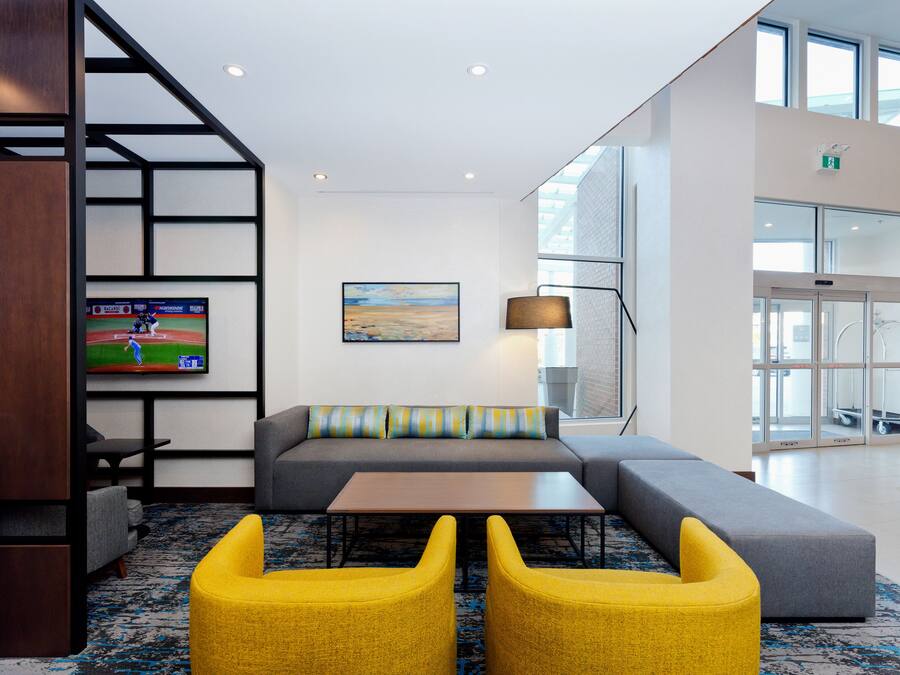 Un hall d’entrée moderne avec un canapé d’angle, un téléviseur à écran plat, une lampe et une moquette à motifs.