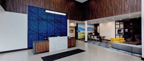 A modern lobby with a reception desk, seating area, and a large wall mural.
