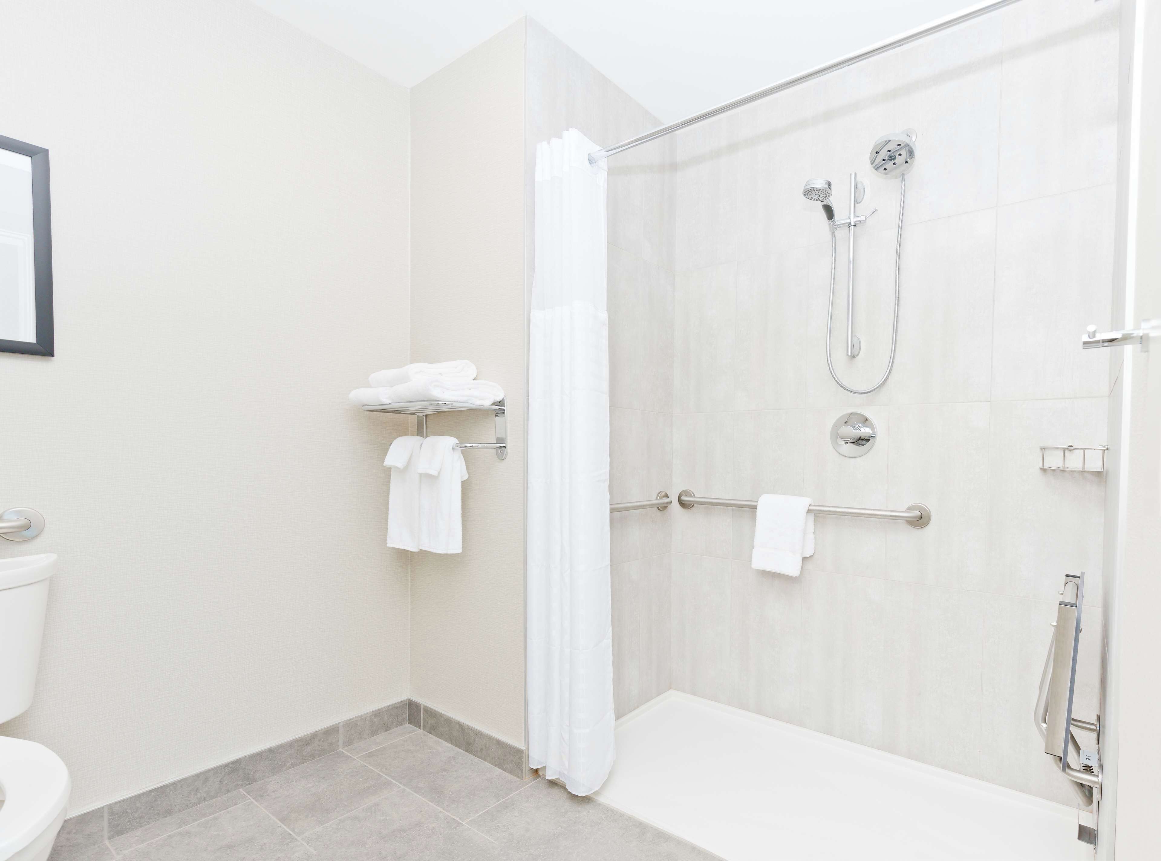 A modern bathroom with a shower, toilet, and towel rack.