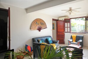 Uma sala de estar com sofá, poltrona e ventilador no teto.