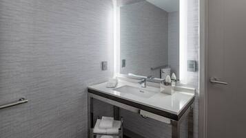 A modern bathroom with a large mirror, a sink, and a towel rack.