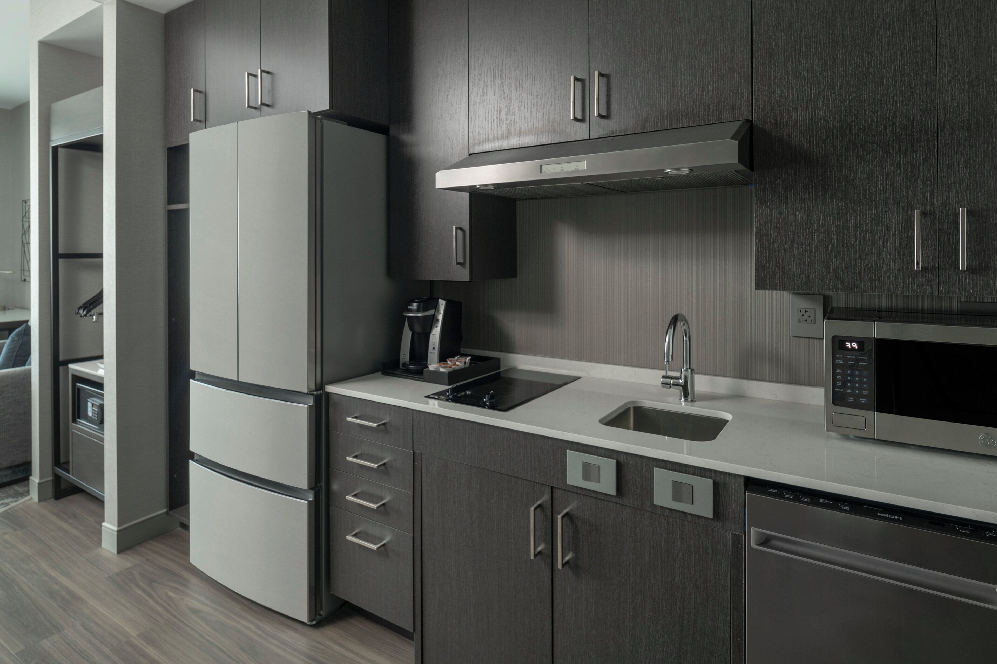 A modern kitchen with a built-in microwave, a coffee maker, and a refrigerator.