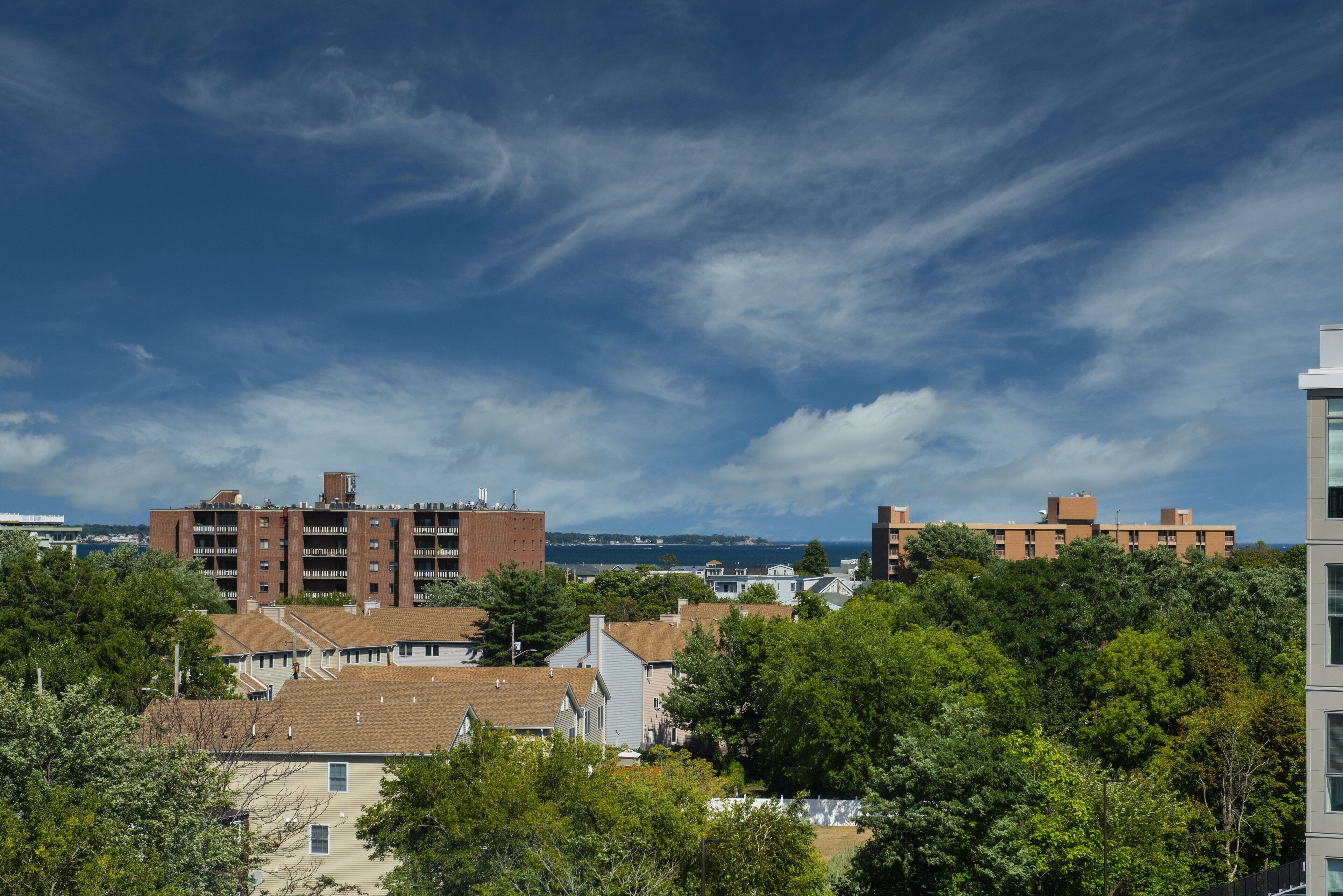 Un barrio residencial con varios edificios de apartamentos de ladrillo, rodeado de árboles y un cielo despejado.
