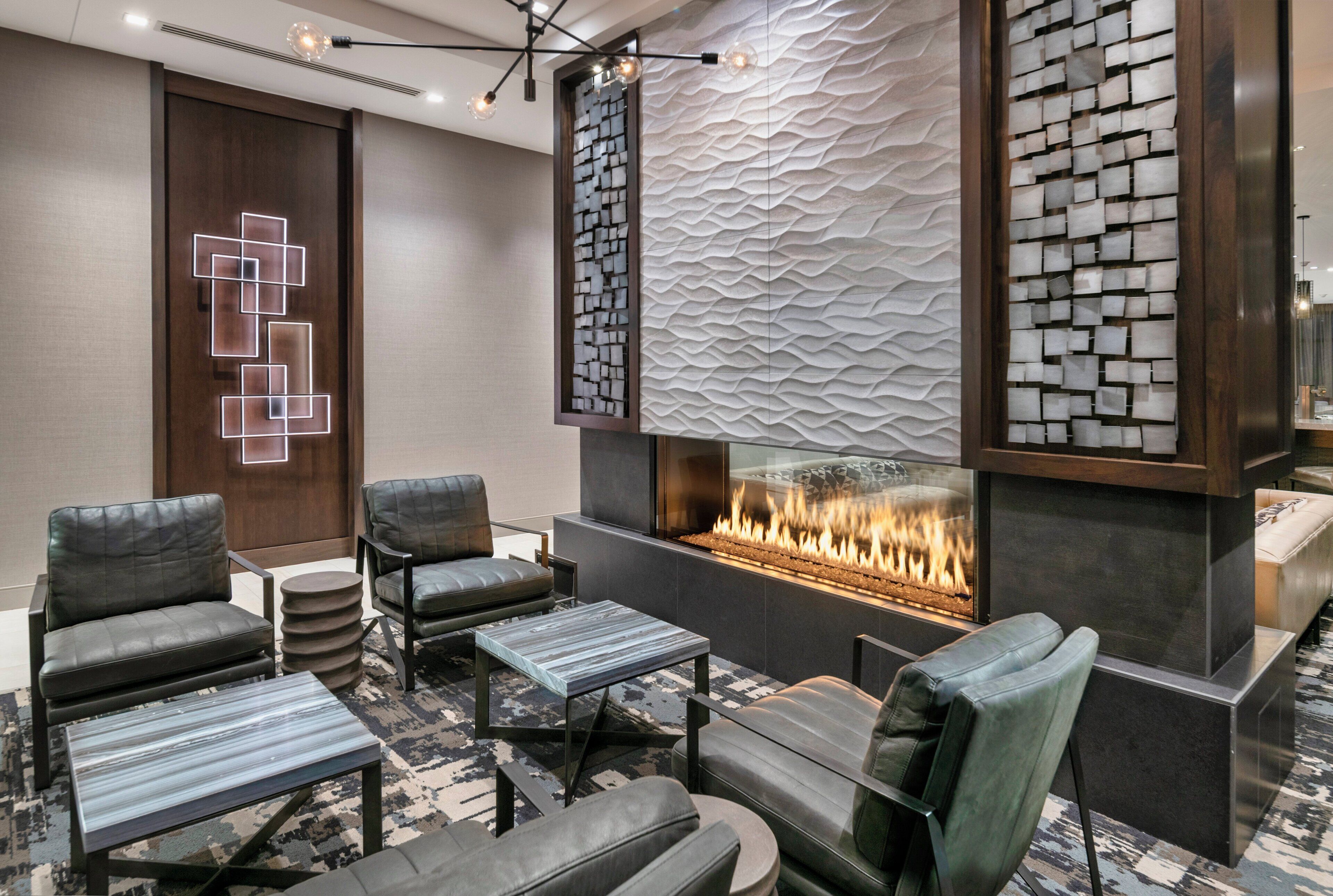 A modern lounge area with leather sofas, a marble coffee table, and a built-in fireplace.
