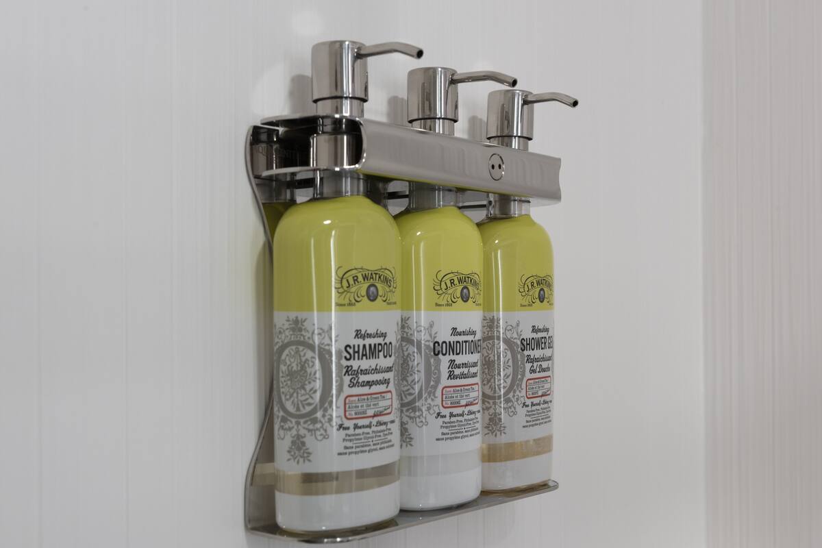 Drei Flaschen J.R. Walker Shampoo und Conditioner in einem Wandspender.
