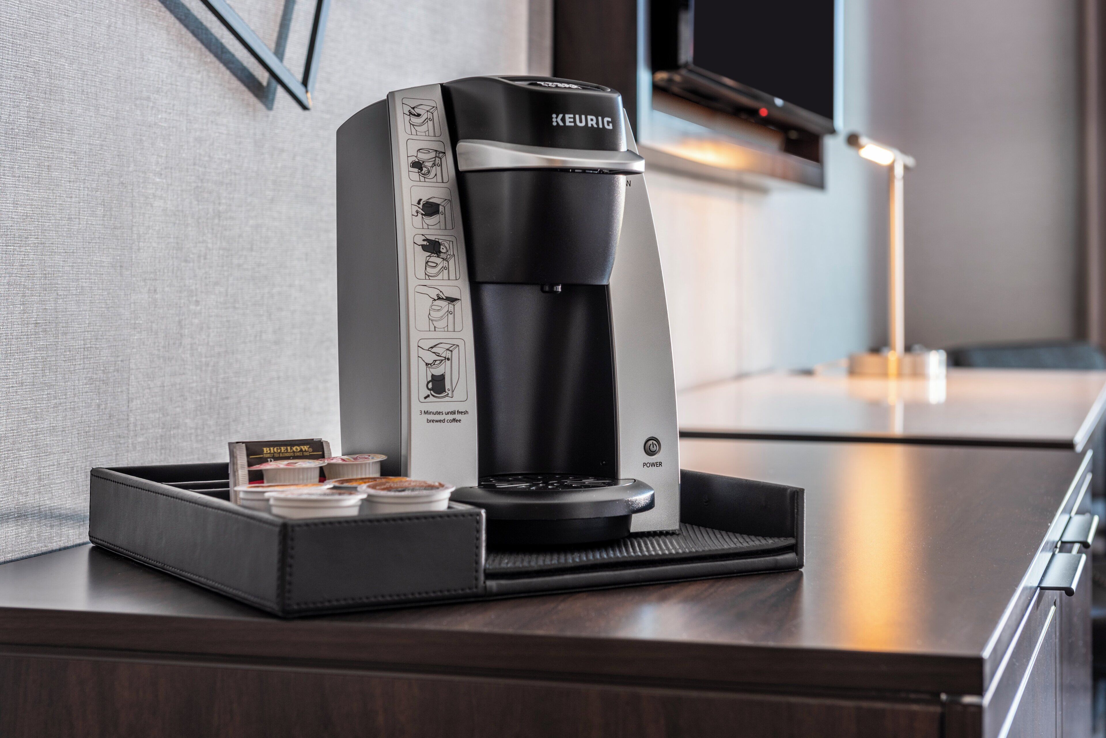 A Keurig coffee maker on a countertop with a tray of coffee pods and a mug.