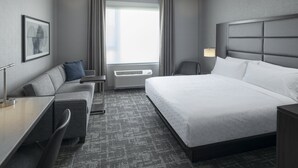Une chambre d’hôtel moderne avec un grand lit, un bureau, une chaise et un canapé.