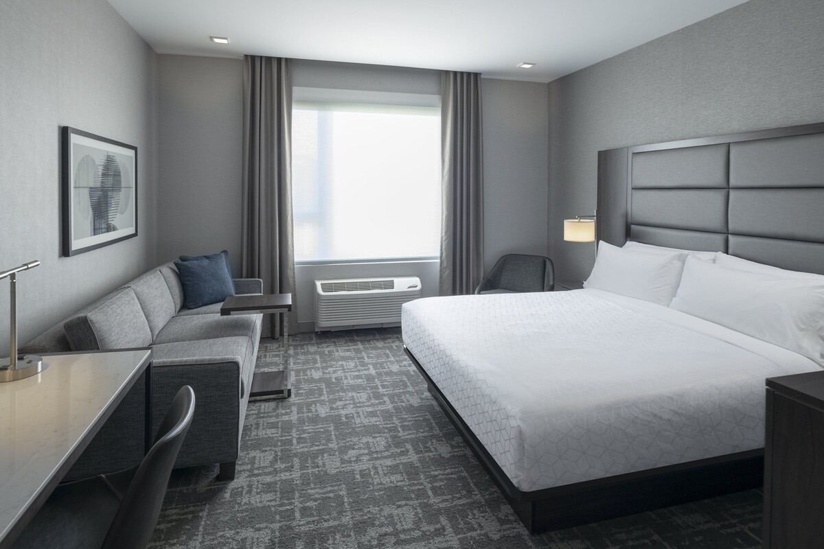 Une chambre d’hôtel moderne avec un grand lit, un bureau, une chaise et un canapé.