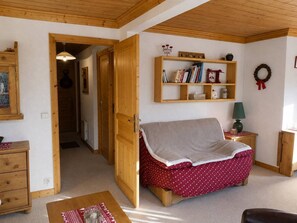 Une pièce chaleureuse avec un canapé en bois, une bibliothèque et une petite table.